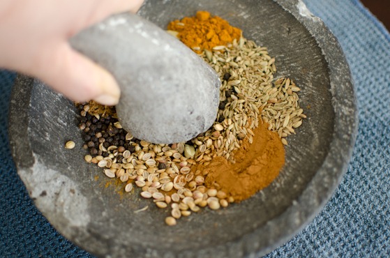 Grind curry spices for Cape Malay chicken curry with a pestle.