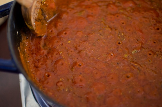 Tomato curry spice mixture is simmering in a blue pot.