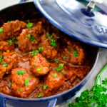 Cape Malay chicken curry is garnished with parsley in a blue pot with a lid
