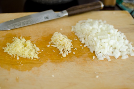 Finely chop onion, garlic, and ginger for making a curry.