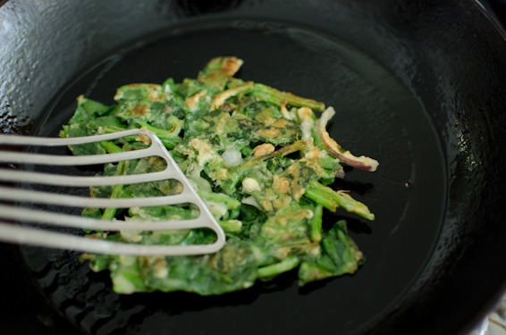 Golden crisp spinach pancake is flipped to the other side.