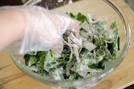 Hand toss the spinach and flour mixture in a bowl.
