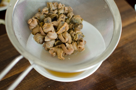 canned sea snail is drained in a colander.