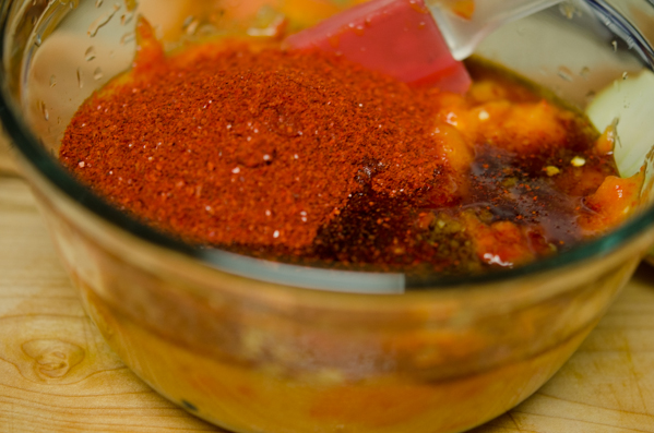 Korean chili flakes are added to persimmon onion puree in a bowl.
