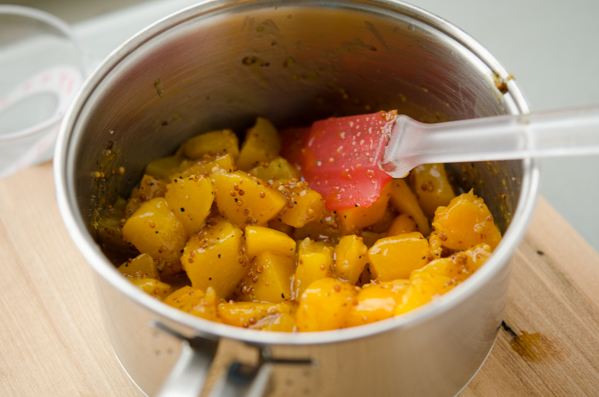 Diced canned peaches added to the glaze in a pan.