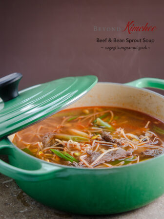 Beef and bean sprouts are simmered together in a green pot.