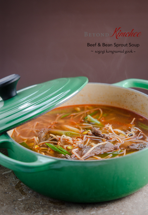 Beef and bean sprouts are simmered together in a green pot.