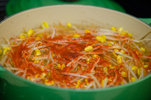 Soybean sprouts and chili flakes are added to the pot of beef soup.