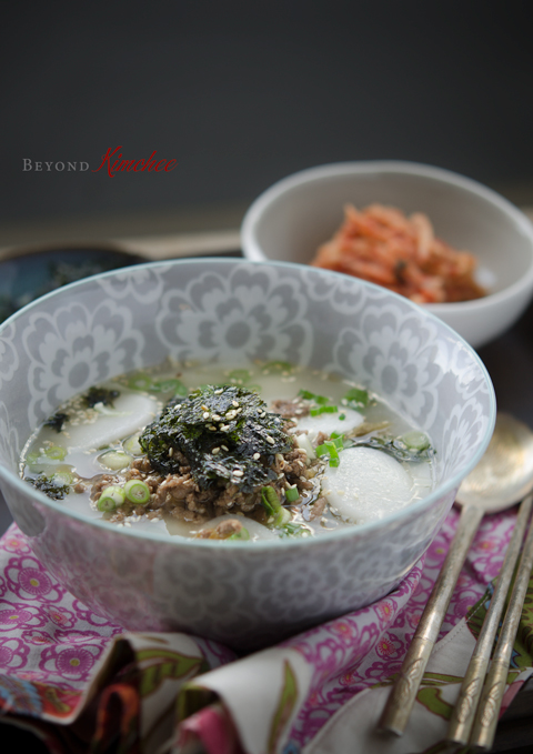Korean rice cake soup is served with kimchi.
