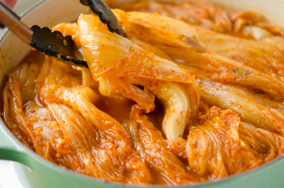 Turning the simmered kimchi to the other side in the middle of cooking time.