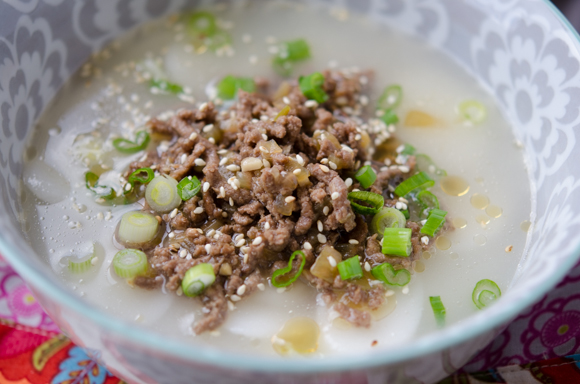 Garnish rice cake soup with chopped green onion and sesame seeds