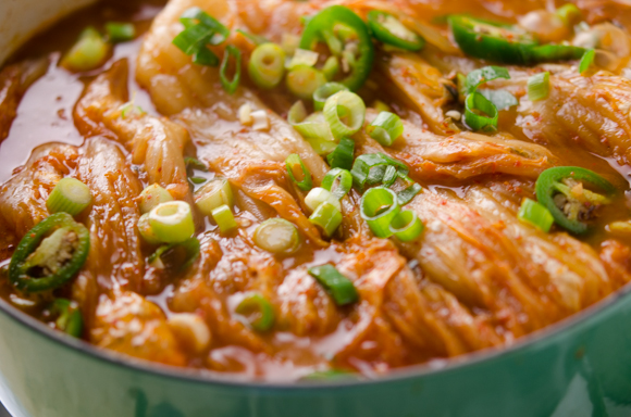 Pork ribs and kimchi are well braised in a pot and garnished with green onion.