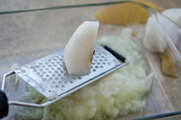 A piece of Korean pear is being grated on a microplane grater.