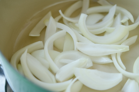 Sliced onions are scattered on the bottom of pot