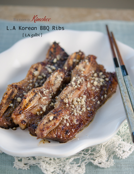Three strips of LA style Galbi are garnished with chopped pine nuts in a white serving platter.