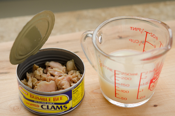 The juice in the canned clam is poured on a glass measuring cup.