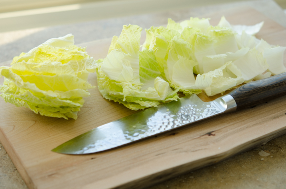 Tender cabbage is cut with a knife.