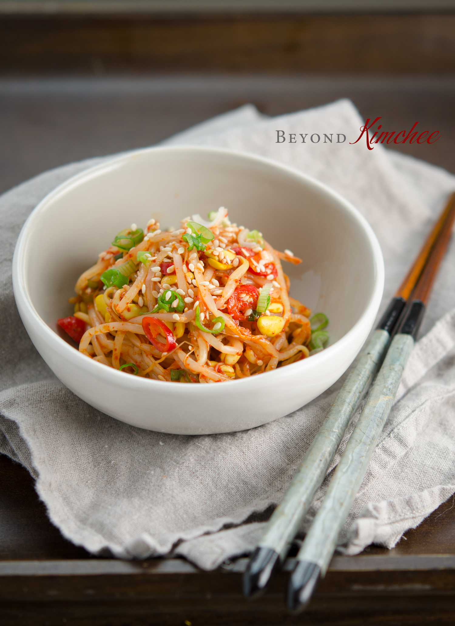 Spicy Bean Sprout salad is served in a small serving dish with napkin and chopsticks.