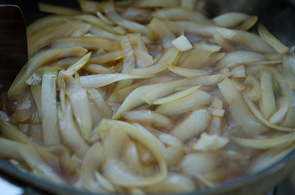 Onion slices are simmering in a soy sauce mixture.