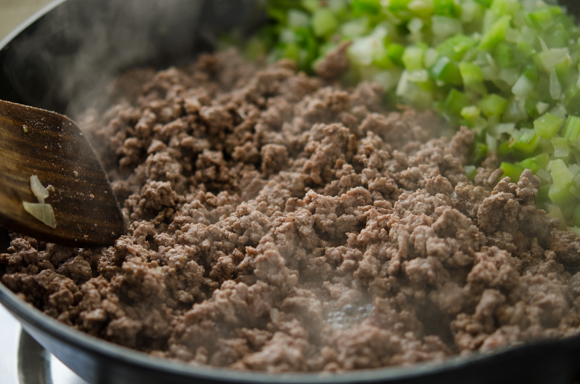 Ground beef is browned to cook completely in a skillet.