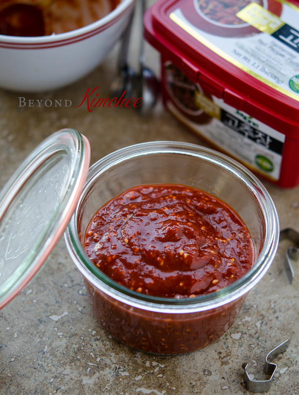 Homemade gochujang sauce is in a glass jar and shows its pretty red color.