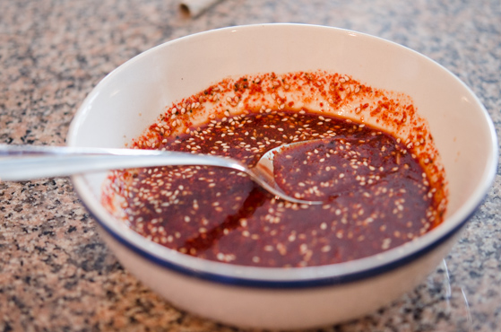 Seasoning paste is made with gochugaru and other ingredients are mixed with a spoon.