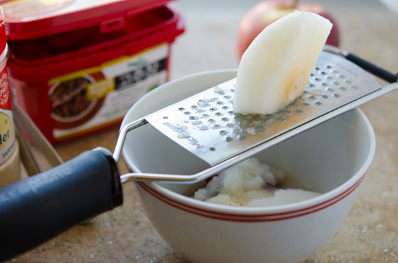 A piece of Korean pear is being grated on a microplane grater.