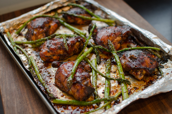Soy Balsamic Chicken Thighs with asparagus on a baking sheet.