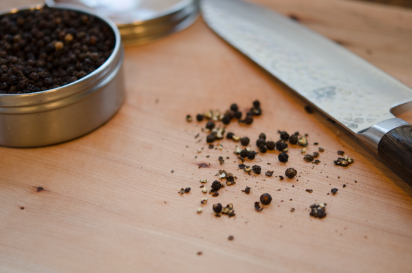 A side of knife is used to crack the whole peppercorns.