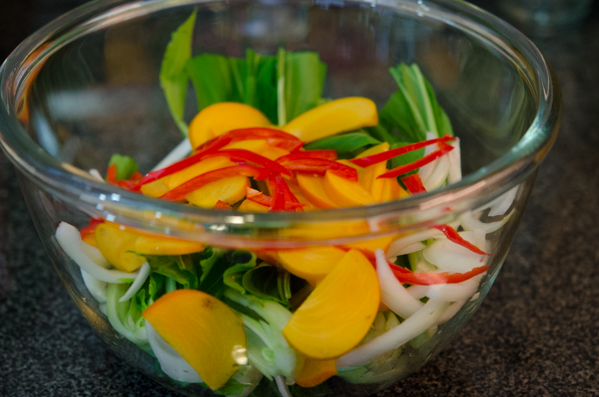 Bok choy and persimmon slices in a bowl.