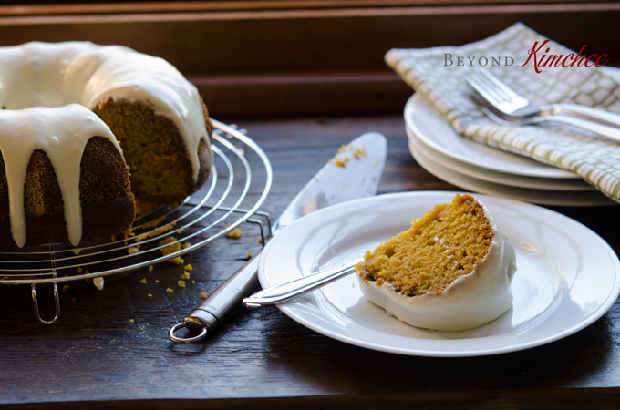 A slice of Pumpkin Bundt Cake with Cream Cheese Maple Glaze is served on a white plate.