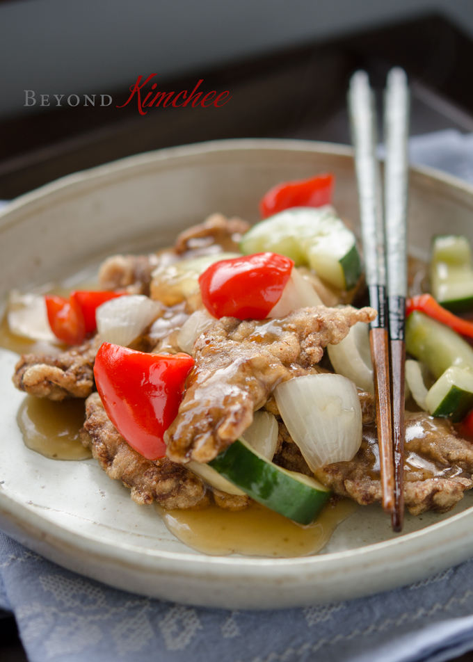 Korean sweet and sour beef is crispy and served with a pair of chopstick.