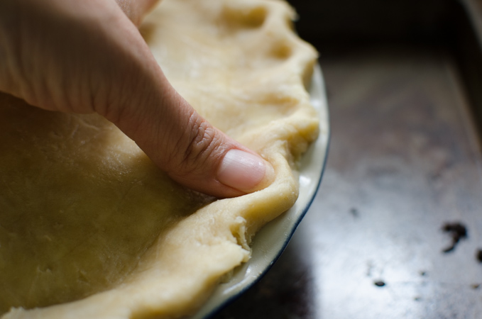 The edges of deep dish apple pie is fluted with a finger