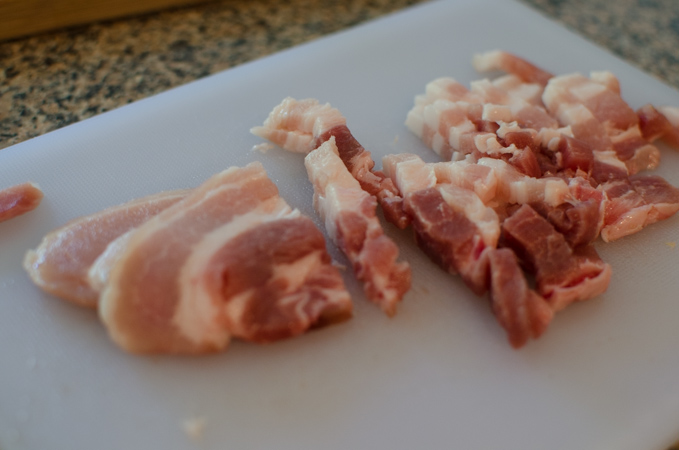 Sliced pork belly on a cutting board.