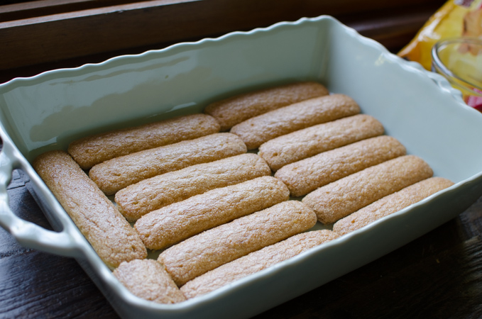 Layers of ladyfinger cookies are placed in a pan.