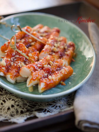 Rice Cakes are on skewers and glazed with sauce made with Korean chili paste (gochujang).