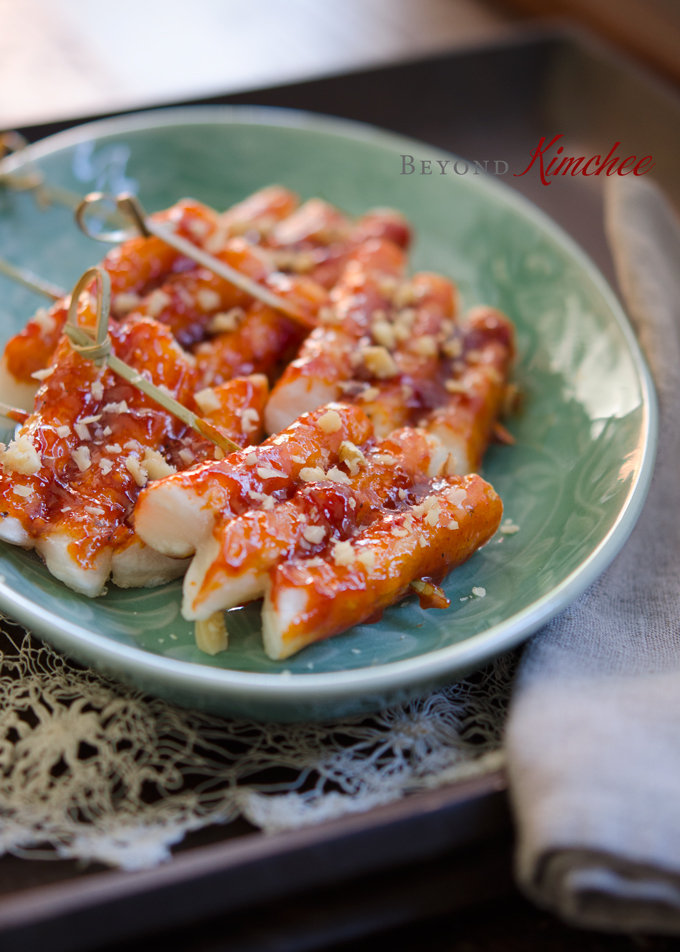 Rice Cakes are on skewers and glazed with sauce made with Korean chili paste (gochujang).