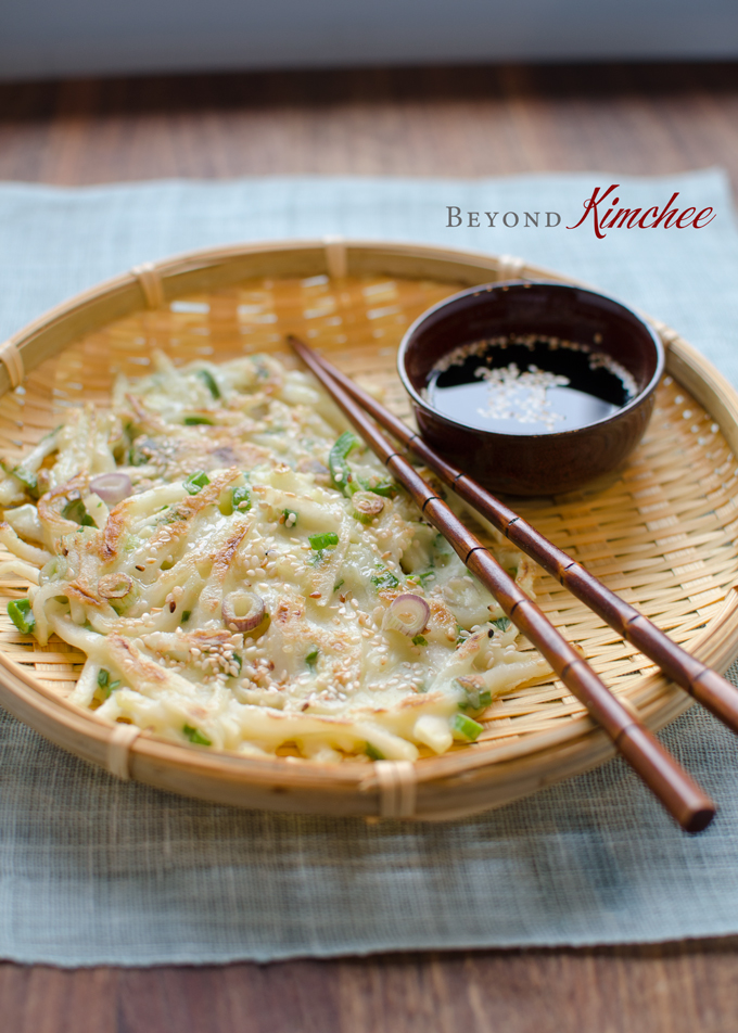 Korean radish pancakes are served on a basket weaved dish with dipping sauce.