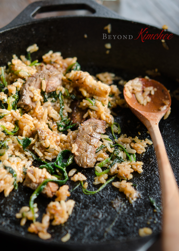 Beef steak and spinach Bibimbap is cooked in a cast iron skillet.