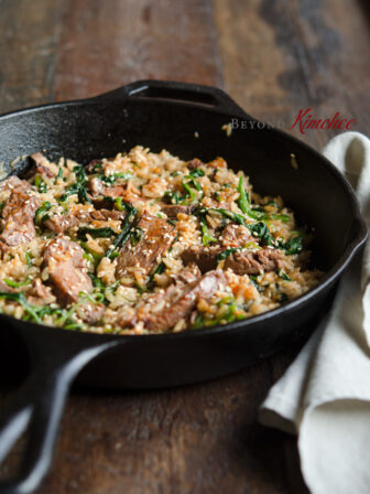 Beef steak and spinach Bibimbap is cooked in a cast iron skillet.