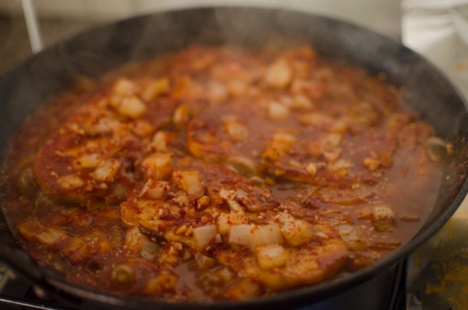 Tofu and the spicy seasoning sauce is simmering in a skillet.