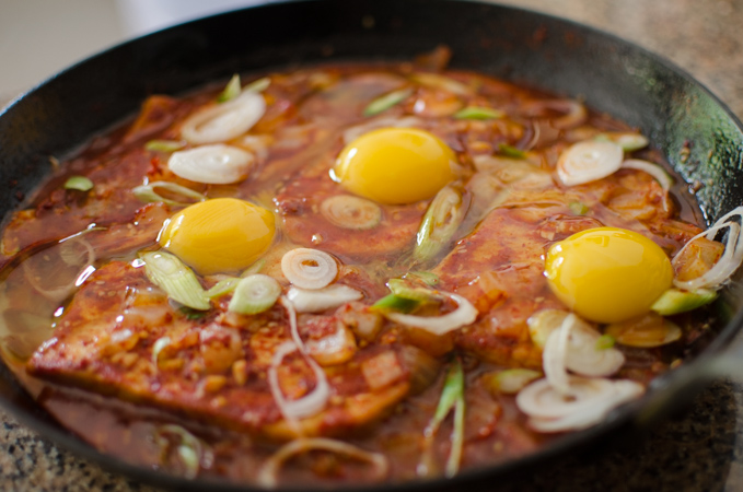 Three eggs are topped on top of tofu in a spicy sauce.