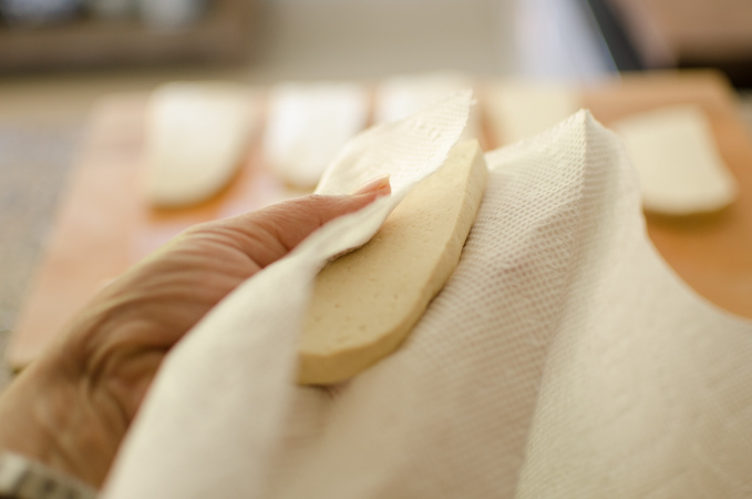 Pressing tofu slices with a paper towel removes the extra moisture.