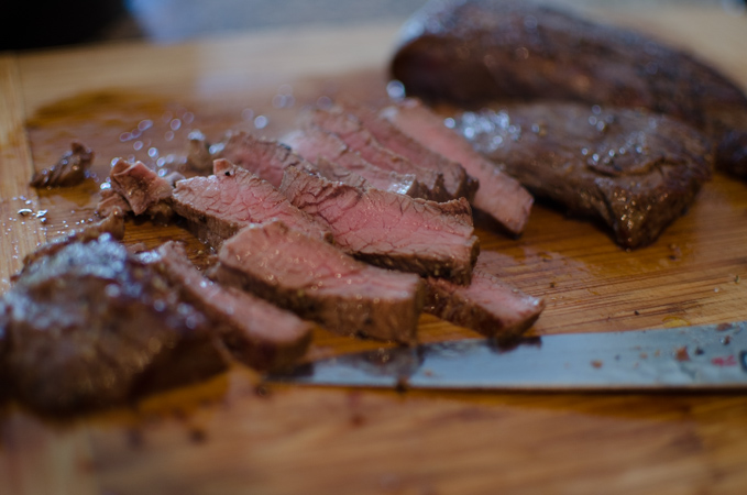 Medium-done beef steak is sliced on a cutting board.