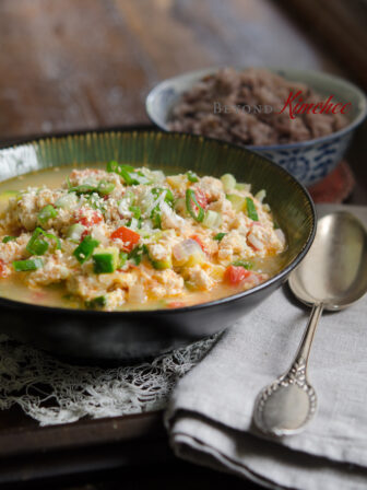 Crumbled soft tofu is cooked with egg and tomato and served with rice.