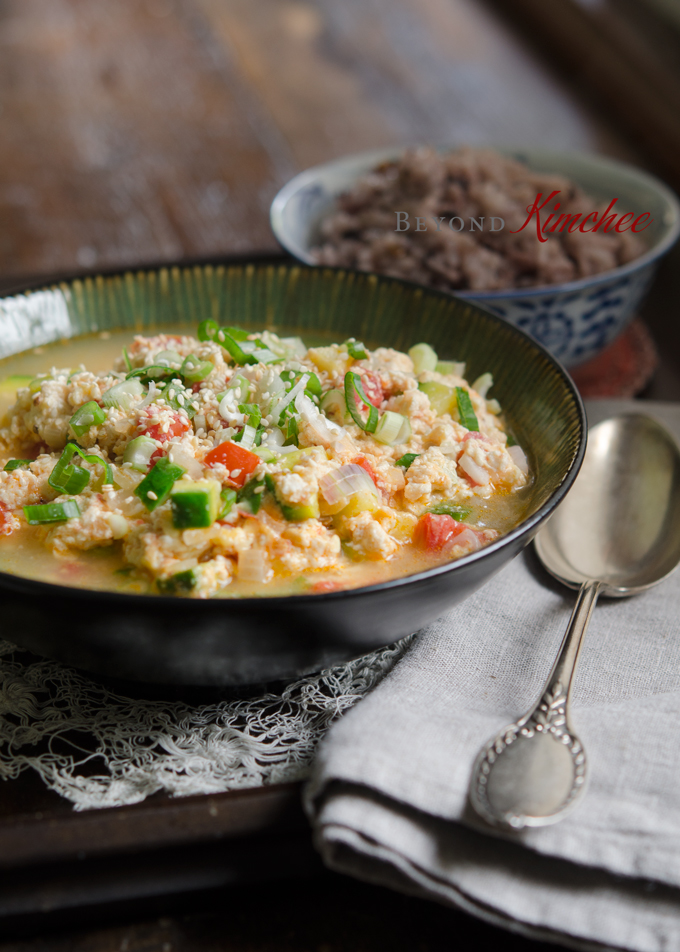 Crumbled soft tofu is cooked with egg and tomato and served with rice.