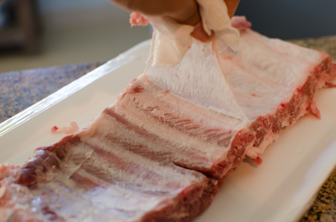 Using a piece of paper towel, pull off the white membrane on the back of pork ribs.