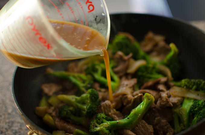 Stir-fry sauce is added to beef and broccoli in a wok.