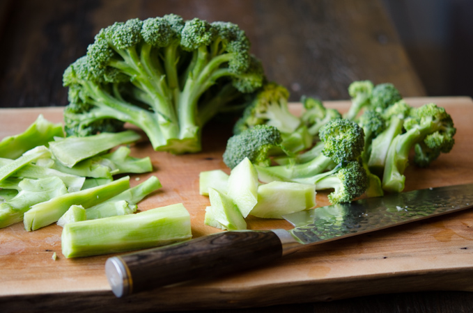 A head of broccoli is cut into florets and stems are saved.