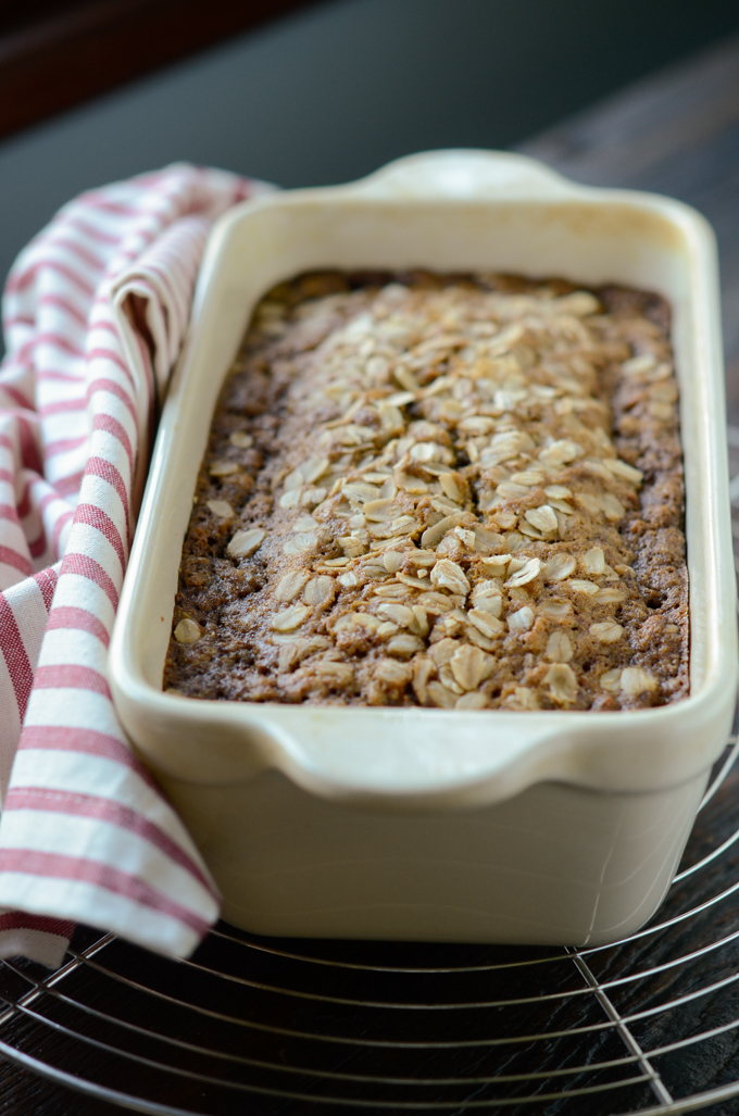 Sweet carrot bread with oats is baked in a loaf pan and is cooling on a wired rack.